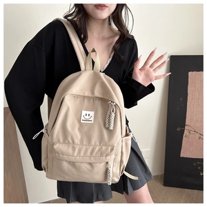 Détail d'un sac à dos en nylon beige avec patch sourire et poche latérale à cordon