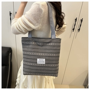 Détail du sac cabas en toile rayée avec texture tissée et bandoulière grise confortable