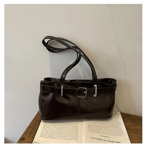 Close-up of a retro dark brown glossy leather underarm bag with decorative belt buckle