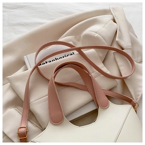 Détail d'un sac seau en PU crème avec poignées et bandoulière roses