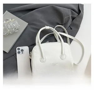 Détail du sac à main blanc en cuir grainé avec logo doré et bandoulière amovible