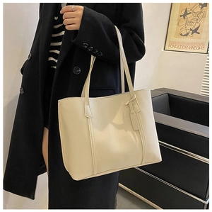 Model wearing a minimalist cream tote bag with vertical stitching and luggage tag detail