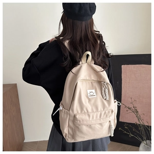 Detail of beige nylon backpack showing adjustable straps and side pockets on a model