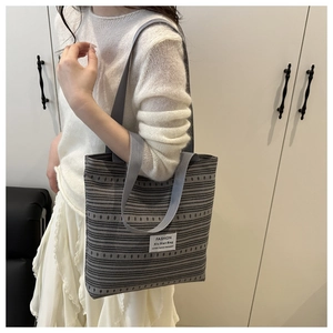 Détail d'un cabas en toile grise avec rayures géométriques et étiquette de marque chic