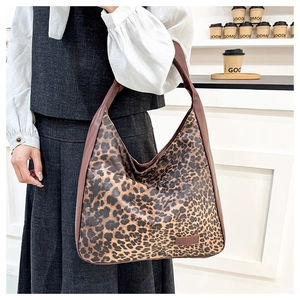 Close-up of leopard print tote bag with brown shoulder strap and minimalist leather patch