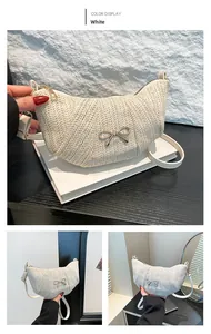 Detail of white woven crescent bag featuring a golden bow metal buckle and slim strap