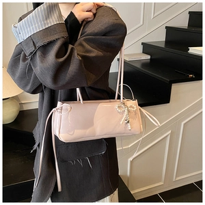 Detail of pink patent leather bag featuring a pearl bow charm and drawstring texture