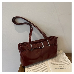 Close-up of retro burgundy shoulder bag with glossy synthetic leather and silver buckle