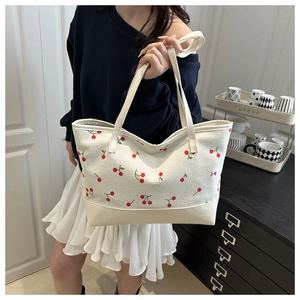 Détail du sac cabas en toile crème avec broderies de cerises rouges et anses en cuir