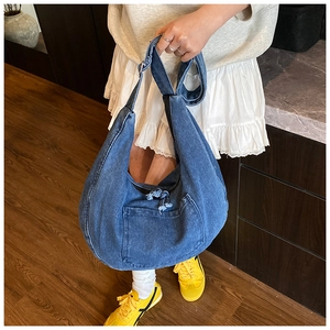 Detail of deep blue denim tote bag with frayed fringe pocket edge and large capacity