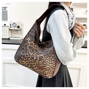 Detail shot of leopard print tote bag texture with brown faux leather trim and strap