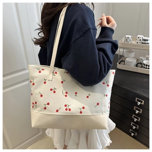 Lifestyle view of a large cream cherry print tote bag with leather base detail