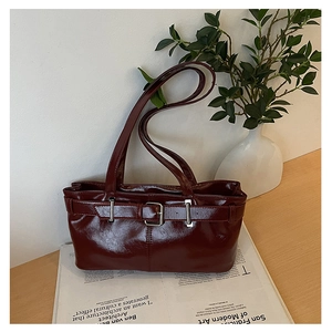 Close-up of a vintage dark red underarm bag with polished leather and strap details