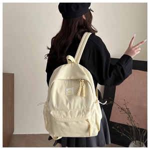 Detail of cream canvas backpack with yellow smiley face patch and woven zipper pulls