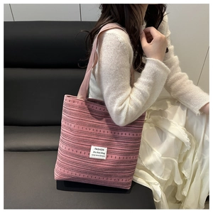 Détail du sac cabas en toile à rayures roses avec étiquette porté par un mannequin