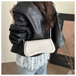 Detail of minimalist cream shoulder bag featuring wavy design and gold logo lettering