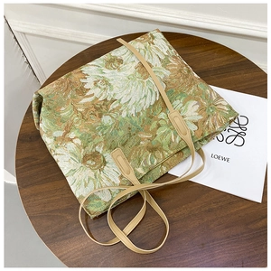 Detail of floral tapestry fabric texture and beige leather handles on the tote bag