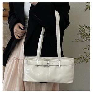 Chic cream white shoulder bag in glossy leather worn by a model in a black blazer