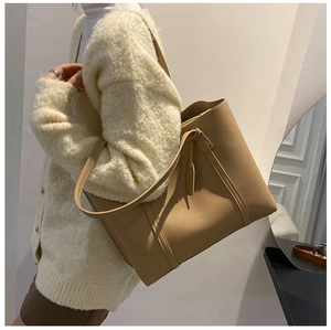Close-up of khaki oversized leather tote bag with long straps and decorative tag