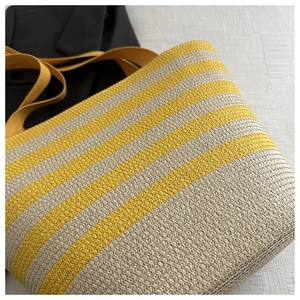 Detail of yellow and beige striped woven tote bag with durable handle and texture