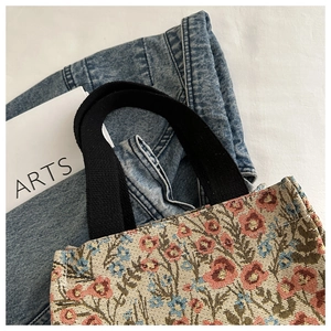 Detail of floral jacquard fabric and thick black woven handle on minimalist tote bag