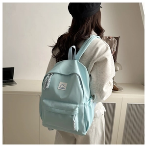 Detailed side view of a light blue casual school backpack with a fashion smiley patch