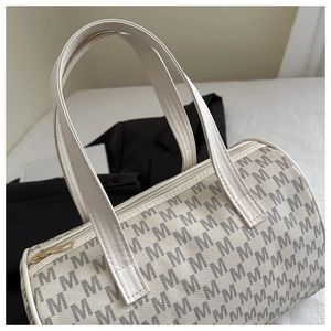 Dettaglio dell'elegante borsa a cilindro bianco crema con motivo M grigio e oro