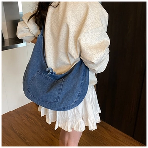 Detail of a large dark blue washed denim shoulder bag with a fringed rope front pocket