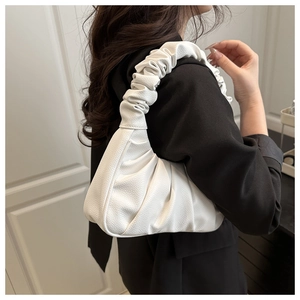 Primo piano di una borsa a tracolla bianca increspata minimalista con blazer nero.