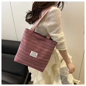 Vue détaillée du sac cabas en maille à rayures roses avec bandoulière et étiquette blanche
