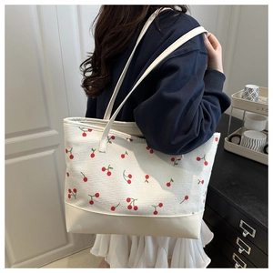 Canvas tote bag with cherry pattern and leather base detail shown on a shoulder