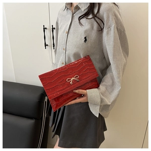Detail of red stone texture PU handbag featuring a golden bow buckle decoration