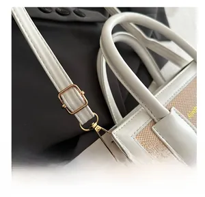 Close-up of golden adjustable buckle on white leather and canvas shoulder bag