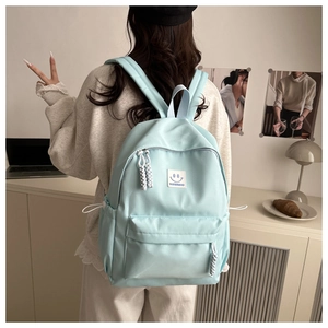 Detail of mint green nylon backpack with front zipper pocket and smiley face logo patch