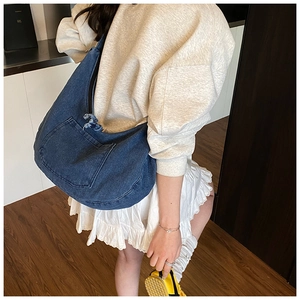 Close-up of large capacity denim crossbody bag featuring deep blue denim and front patch pocket