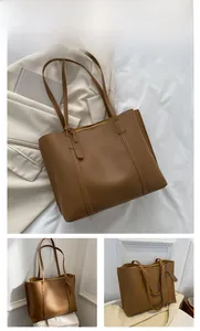 Detail view of large brown faux leather tote bag with fine matte texture and double handles