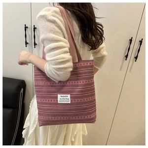 Détail d'un sac cabas en tricot rose avec motifs violets et larges bretelles confort