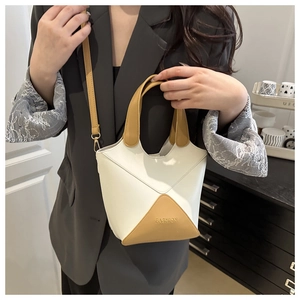Sac seau rétro bicolore tenu par un mannequin portant un blazer gris élégant