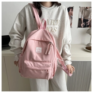 Detail of pink water-resistant nylon backpack with smiley face patch and zipper pull