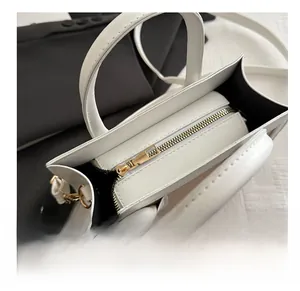 Close-up of golden metal zipper and stitching on white leather crossbody tote bag