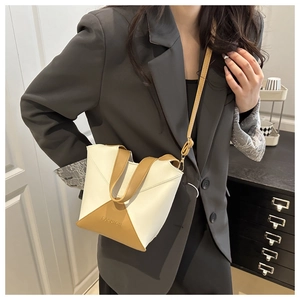 Sac seau élégant en cuir PU bicolore porté avec un blazer gris pour un look chic et moderne