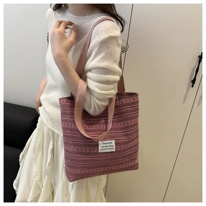 Sac fourre-tout en toile à rayures roses avec étiquette porté à l'épaule sur modèle