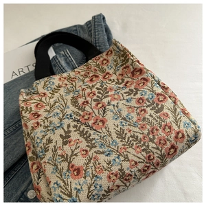 Close-up of vintage floral tapestry fabric and black strap of this tote bag