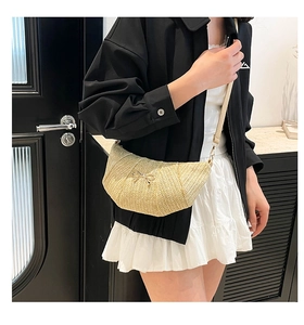 Close-up of straw crescent bag featuring natural texture and golden bow ornament