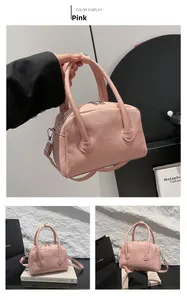 Detailed close-up of pink lychee grain leather crossbody bag with dual handles and zippers