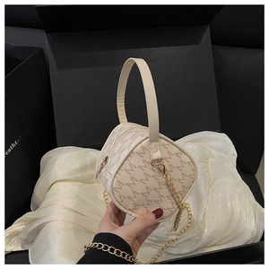 Detail showing pattern texture, golden chain strap, and smooth zipper of the handbag
