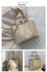Detail view of the cream white soft leather tote bag with long shoulder straps and pendant