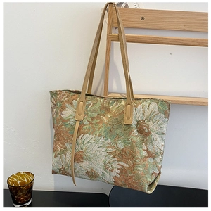 Detail of artistic floral jacquard tote bag with leather straps and daisy patterns
