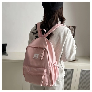 Detailed back view of a pink nylon backpack with a smile label and woven zip puller