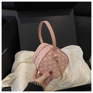 Detail of light pink box-shaped handbag with M-pattern print and gold chain strap